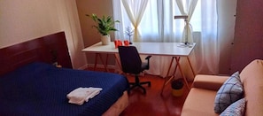 A hotel room with a bed, a desk, a chair, a sofa, and a window with curtains. - Insta Hostel Floripa (Florianópolis)