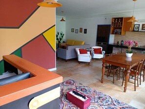 A modern living room with a sofa, chairs, a dining table, and a kitchen area. - Insta Hostel Floripa (Florianópolis)