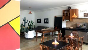 Una sala de estar moderna con comedor, que incluye una cafetera, un cuadro de pared con un cactus y una zona de estar acogedora.