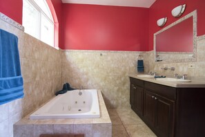 A bathroom with a bathtub, two sinks, and a large mirror.