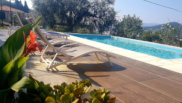 A poolside area with lounge chairs and a view of the pool. - App.in semi-detached villa private garden and parking shared pool (Imperia)