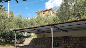 A covered outdoor area with a gravel ground, stone wall, and a building in the background. - App.in semi-detached villa private garden and parking shared pool (Imperia)
