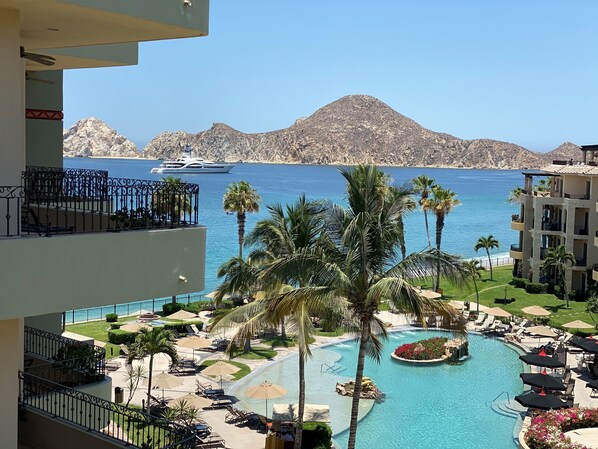 Un complexe hôtelier doté d’une piscine, de palmiers et offrant une vue sur la mer et les montagnes.