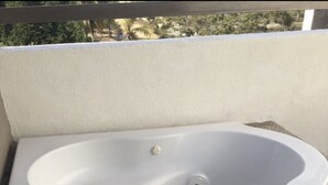 Una tina de hidromasaje blanca con asiento integrado, sobre una encimera de granito.
