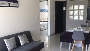 Una sala moderna con un sofá gris, un tapete morado y un comedor con una mesa y sillas.