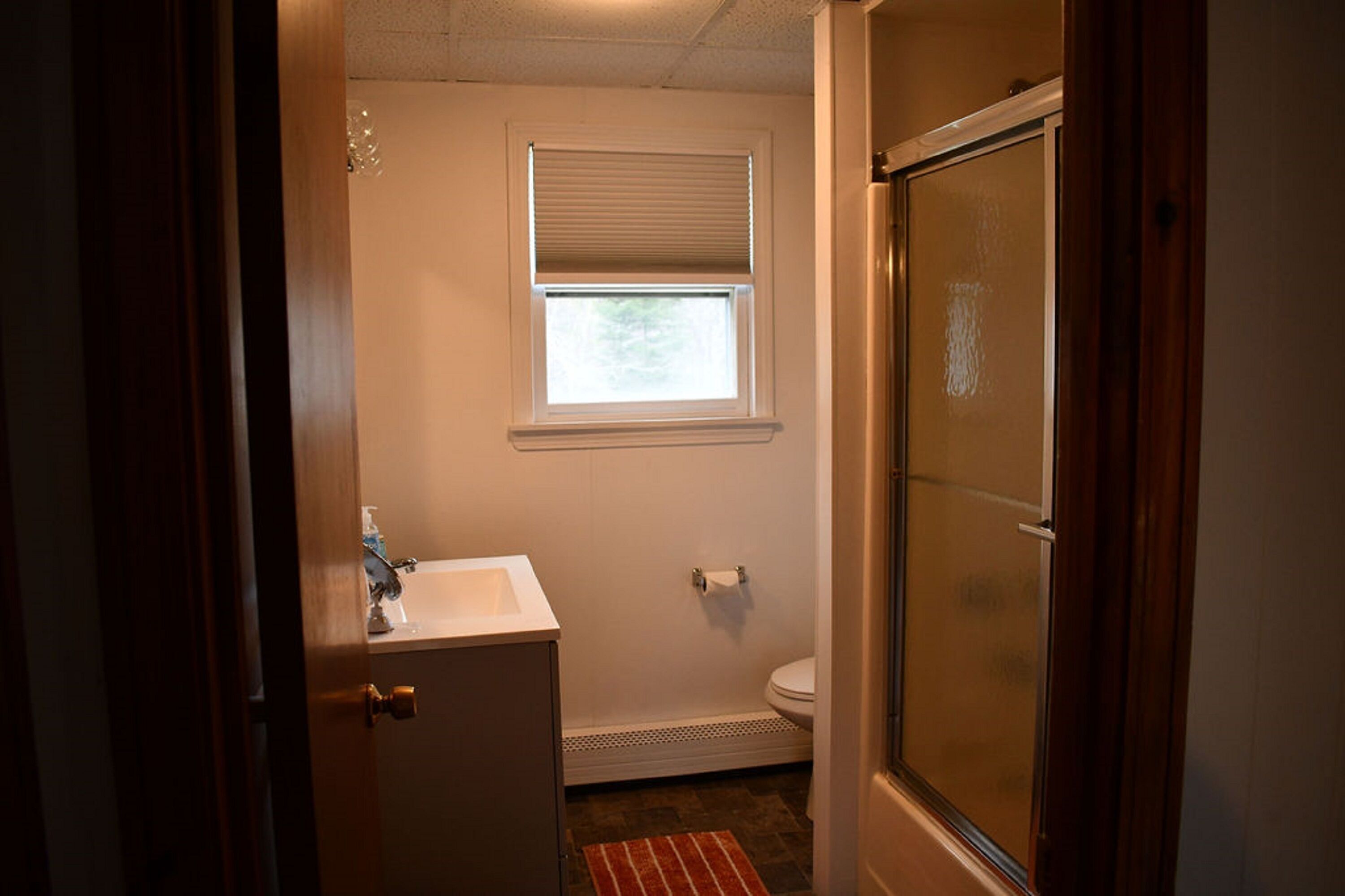 Un baño con inodoro, lavamanos, ventana y ducha.