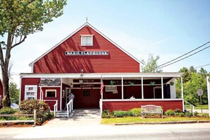 Um edifício vermelho em estilo de celeiro com uma placa que diz 'Barn Playhouse'.
