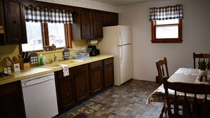 A kitchen with wooden cabinets, a white refrigerator, and a dining table with chairs. - Brook Road Condo (Goshen)