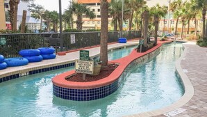 Area piscina con una piattaforma galleggiante, palme e un cartello che indica una profondità di 75 centimetri.