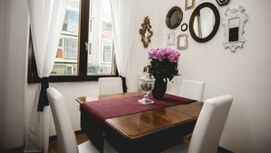 A dining area with a wooden table, white chairs, a red table runner, and a vase with flowers. - St. Peter's Heart -honeymoon luxury apartment Rome (roma)