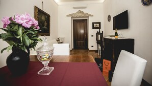 A dining area with a table set for two, a vase of flowers, and a television mounted on the wall. - St. Peter's Heart -honeymoon luxury apartment Rome (roma)