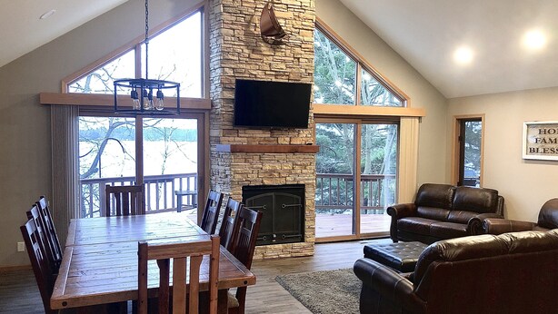 A spacious living area with a stone fireplace, a large dining table, and leather seating. - Full Rec Lake w/pontoon to rent! 🏖 Beach. 🐶 friendly. (Wautoma)