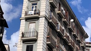 A multi-story building with balconies, a visible window, and a satellite dish.