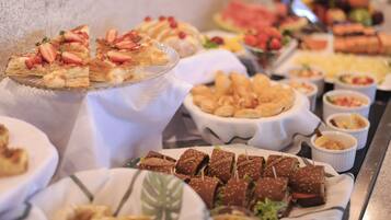 A buffet with various food items including pastries, sandwiches, and fruit.