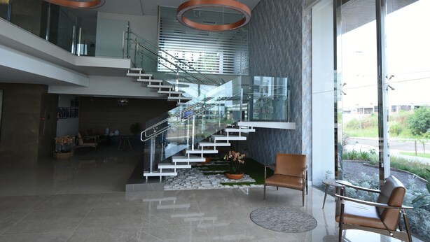 A modern interior with a glass staircase, seating area, and large windows. - Figueiras Hotel & Eventos (Sao Miguel Do Oeste)