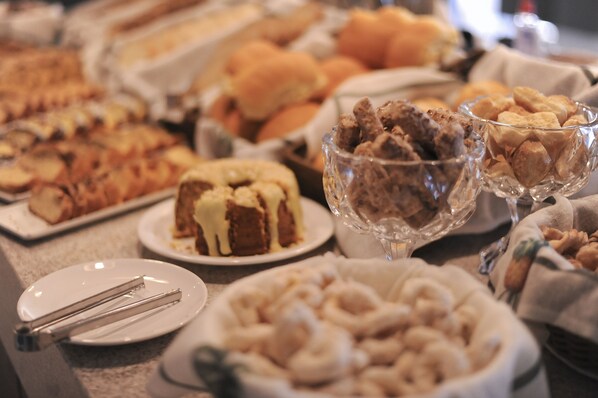 Una mesa de buffet con diversos platos, incluyendo un pastel, galletas y otras preparaciones horneadas.