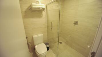 Ein modernes Badezimmer mit einer begehbaren Glasdusche, einer Toilette und einem Handtuchhalter.