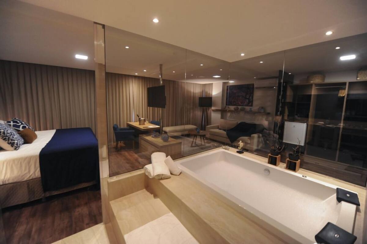 Una habitación de hotel moderna con una bañera grande, un sofá, un escritorio y un televisor.