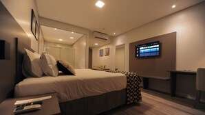 A modern hotel room with a large bed, bedside table, and a TV mounted on the wall. - Figueiras Hotel & Eventos (Sao Miguel Do Oeste)