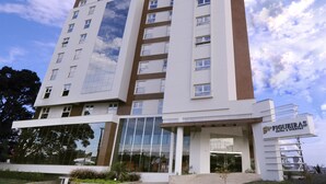 A modern hotel building with a prominent glass facade reflecting the sky, multiple floors, and a visible entrance with a sign reading "FIGUEIRAS HOTEL & EVENTOS". - Figueiras Hotel & Eventos (Sao Miguel Do Oeste)