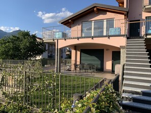 A two-story building with a balcony, outdoor seating area, and a staircase. - Pool apartment in quiet and central area (Colico , Lombardei)
