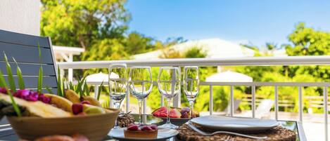 A table set for a meal with a view of lush greenery and a clear sky.