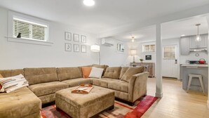 Ein modernes Wohnzimmer mit einem Ecksofa, einem Couchtisch und einer dahinterliegenden Küchenzeile.