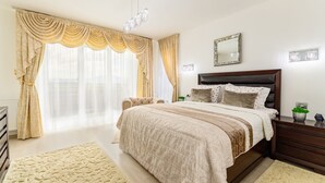 Une chambre à coucher avec un grand lit, une table de chevet, une commode, un miroir et une fenêtre avec des rideaux.