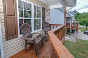 A wooden deck with two Adirondack chairs, a wooden railing, and a view of a neighboring house. - Close to PF Parkway, spacious & clean 3 bedroom! Hot tub and outdoor TV on deck! (PIGEON FORGE)