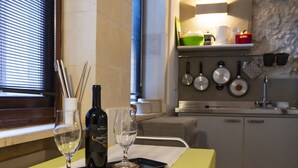 A kitchen with a dining table set for two, featuring wine glasses and a bottle on a tray.