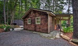 Escape to a serene forest retreat with a cozy cabin featuring a pitched roof and a welcoming front porch.