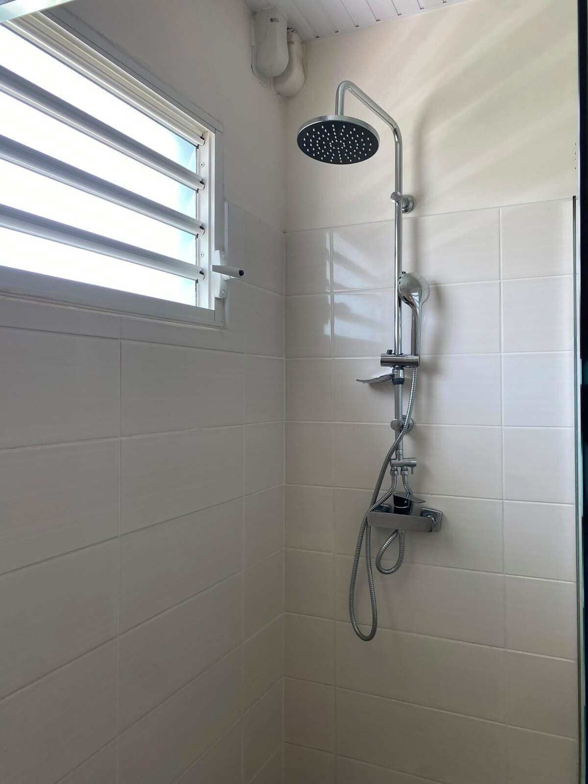 A shower with a handheld showerhead, a wall-mounted faucet, and a handheld hose.