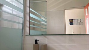 A bathroom with a large mirror, a towel on the counter, and a bottle of soap. - Apartment 30 metres from the beach (Sainte-Luce)