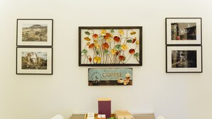 A dining area with a table set for two, a tray with food and drinks, framed pictures on the wall, and a coffee-themed sign.