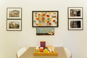 A dining area with a table set for breakfast, including bread, juice, and coffee.
