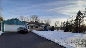 A residential driveway with a garage, a parked car, and snow on the ground.