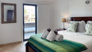 Un dormitorio con cama, espejo, lámpara y vistas al exterior.