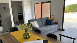 Una sala de estar moderna con un sofá gris, alfombra amarilla y un jarrón verde sobre una mesa de madera.