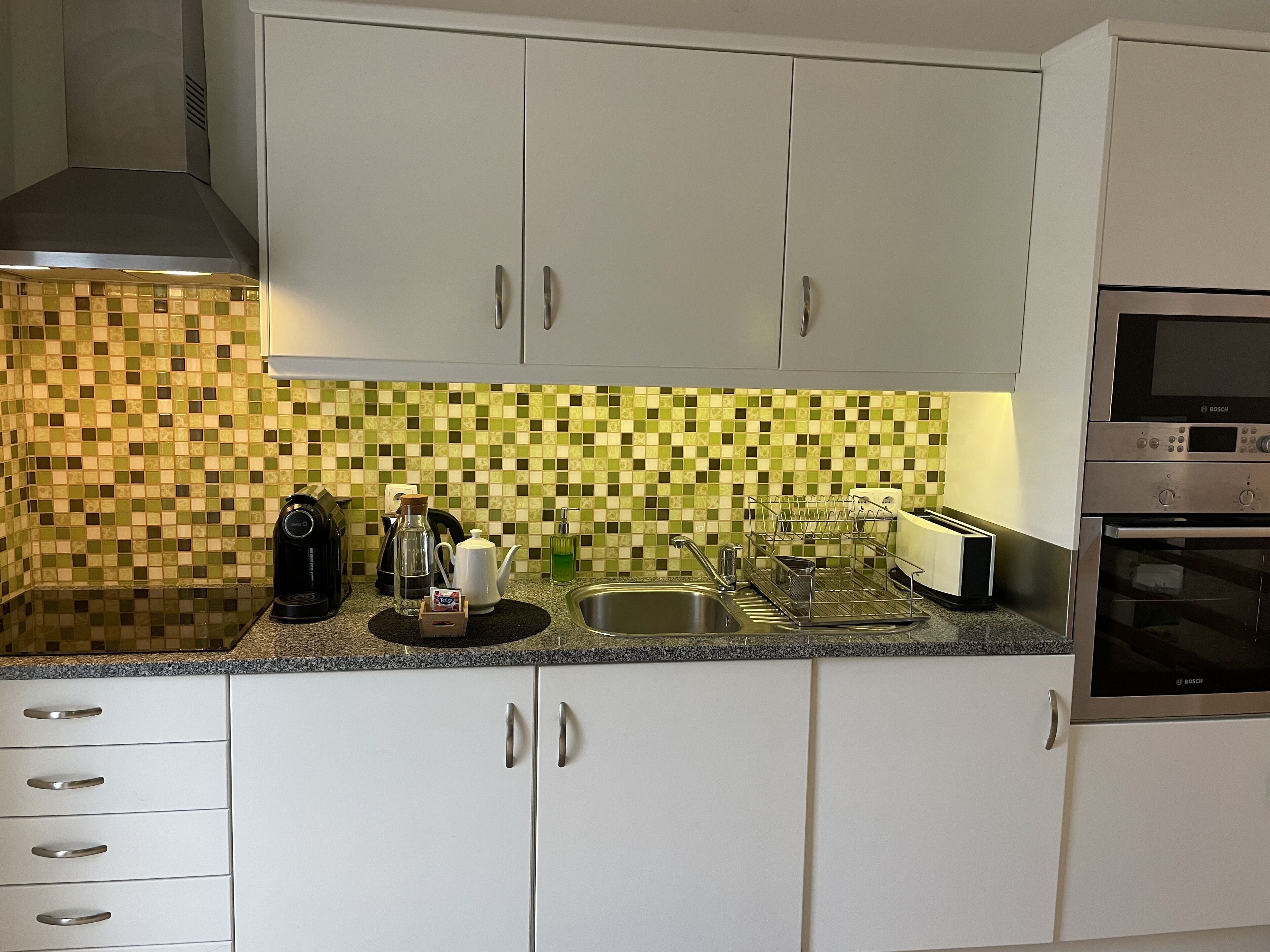 A kitchen with white cabinets, a Bosch microwave, and a sink.