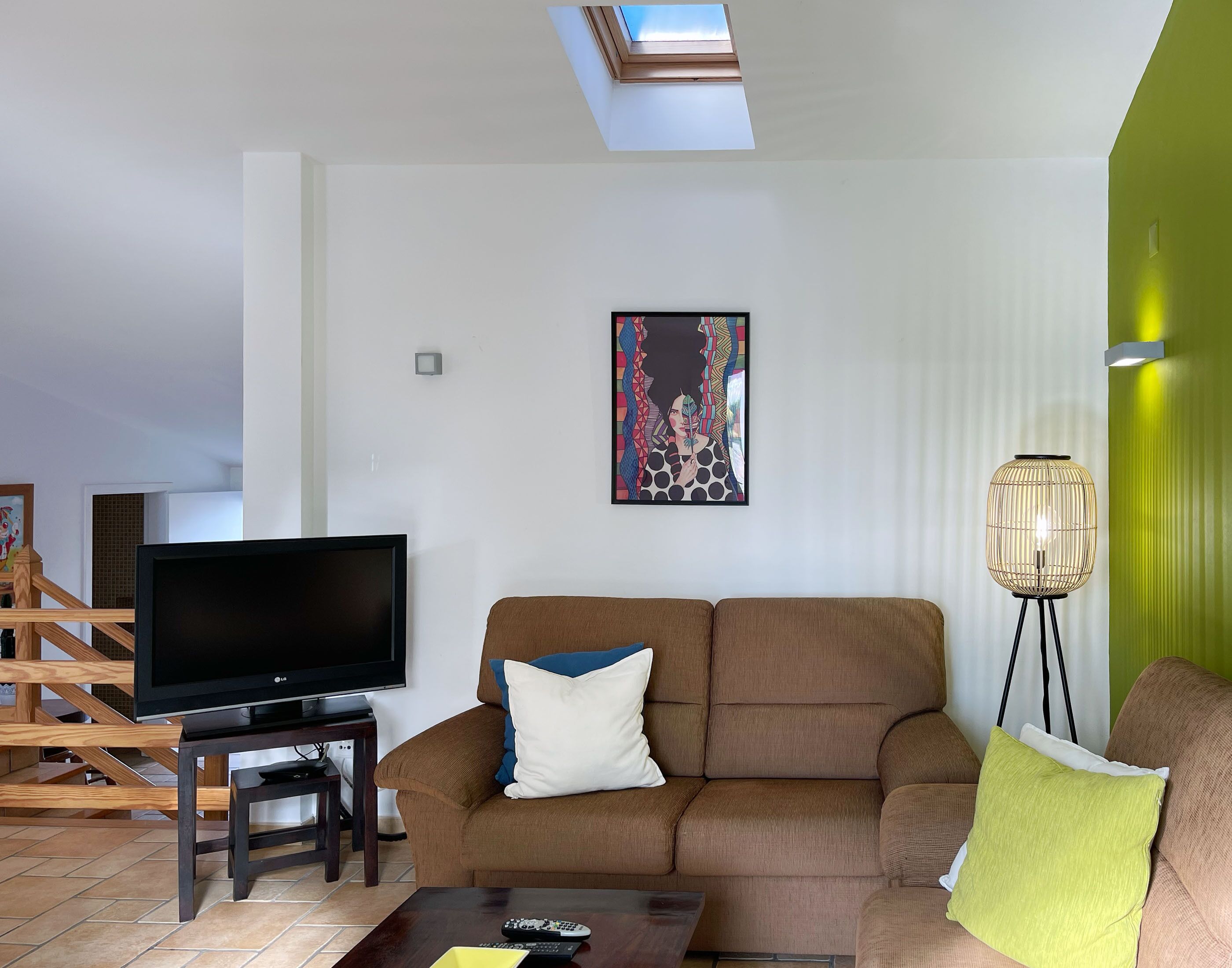 Una sala de estar con un sofá, televisor, una mesa de centro y una lámpara de pie.