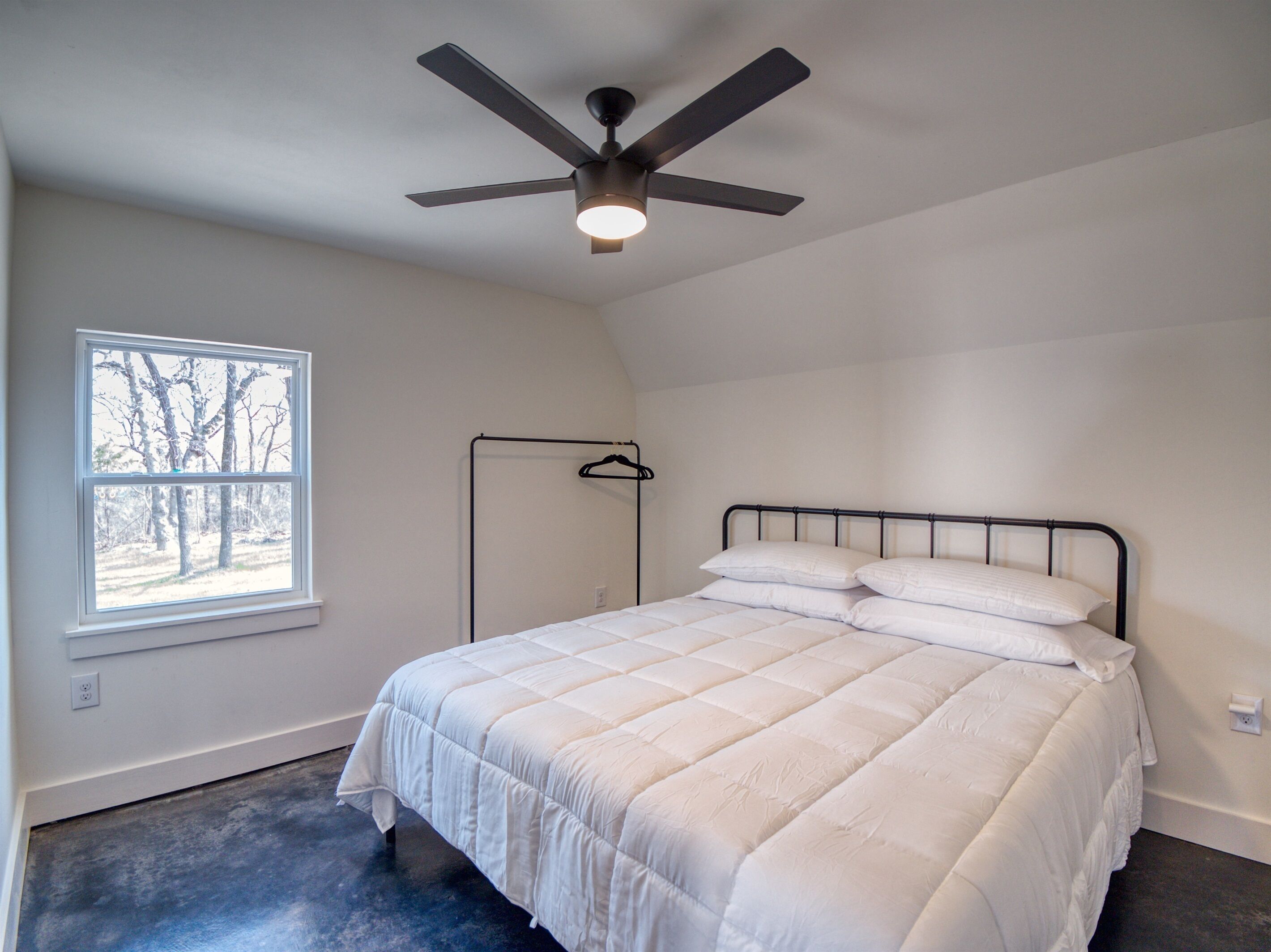 A bedroom with a bed, a ceiling fan, a window, and a door.