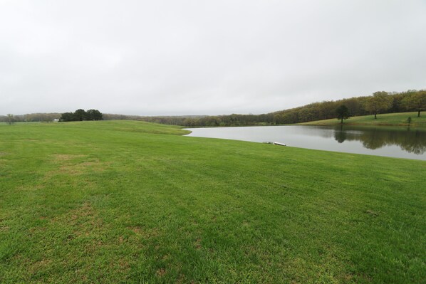 A grassy field with a lake and trees in the background. - Cabool Lake View Country Getaway (Cabool)