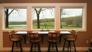 Een keuken met een groot raam, een tafel en vier barkrukken.