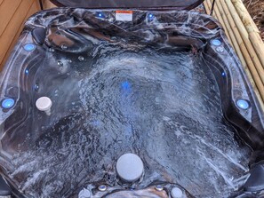 Ein Whirlpool mit klarem Innenraum, umgeben von Holzstämmen.