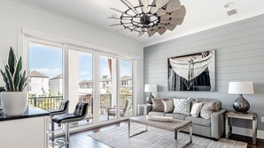 Un salon moderne doté d’une grande fenêtre, d’un ventilateur de plafond, d’un canapé, d’une table basse et d’une plante en pot.