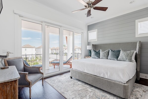A bedroom with a large bed, a chair, a desk, and a ceiling fan.