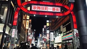 Une rue animée de la ville, de nuit, avec des enseignes et des devantures de magasins illuminées.
