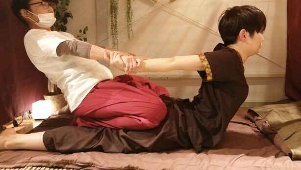 Une personne effectue un massage sur une autre personne assise sur un lit.