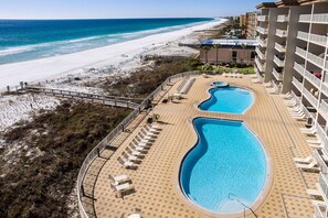A resort with a pool area, beach access, and a view of the ocean.