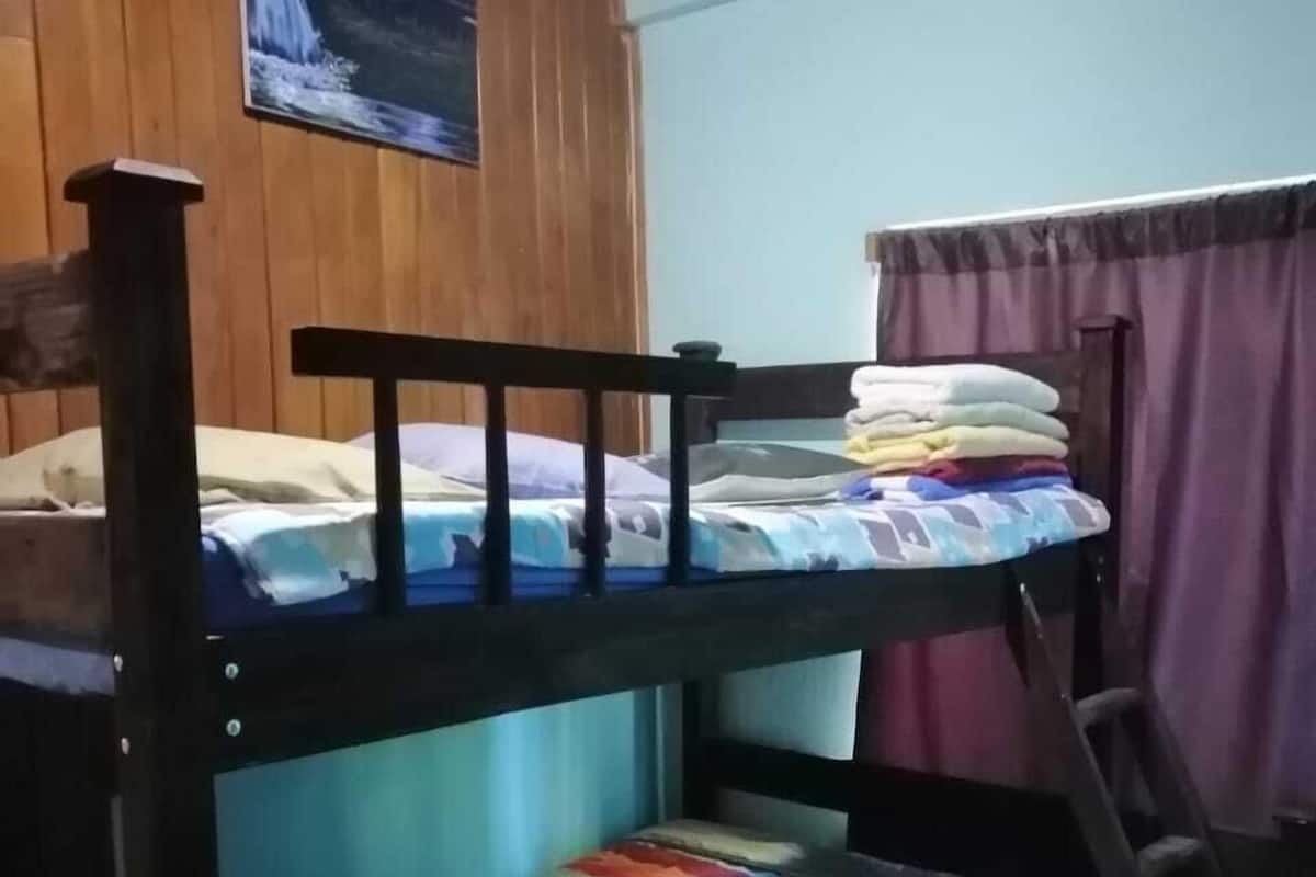 A bunk bed with a wooden headboard, a colorful bedspread, and a night sky poster on the wall.